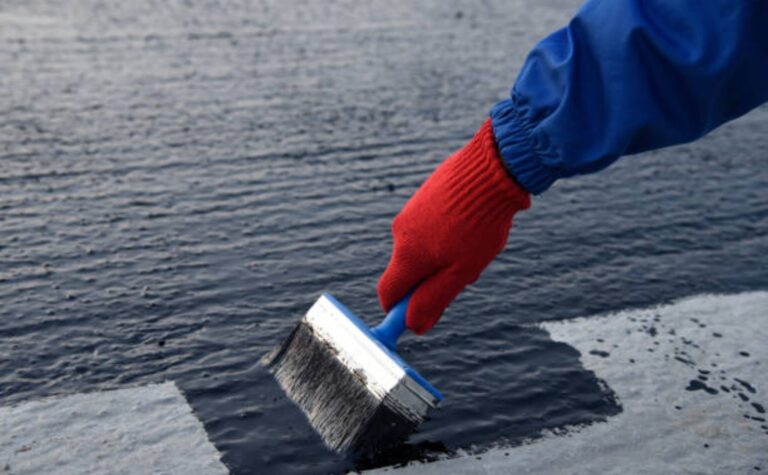 Applying hot bitumen mastic to concrete base for sealing and insulation.