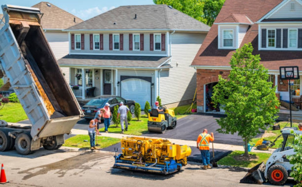 Asphalt paving crew applying a new layer of pavement on a driveway.