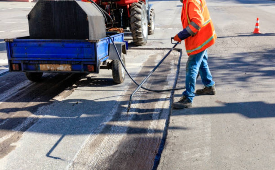 Professional spraying of asphalt binder during road repair work