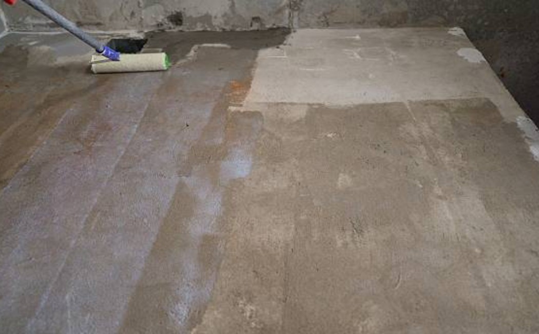 Man applying protective coating to a concrete slab at a construction site