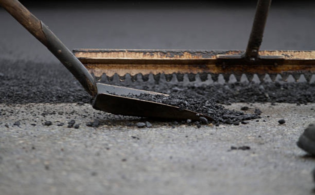 Worker applying asphalt to pave a road surface
