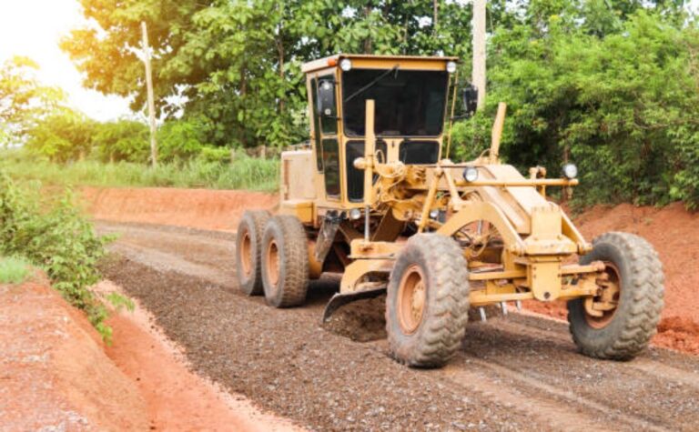 Grader preparing gravel road for asphalt installation