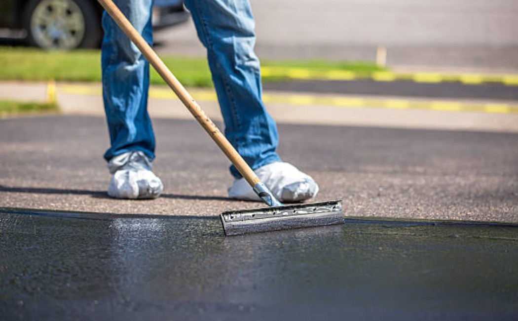 DIY driveway being sealed with black asphalt coating
