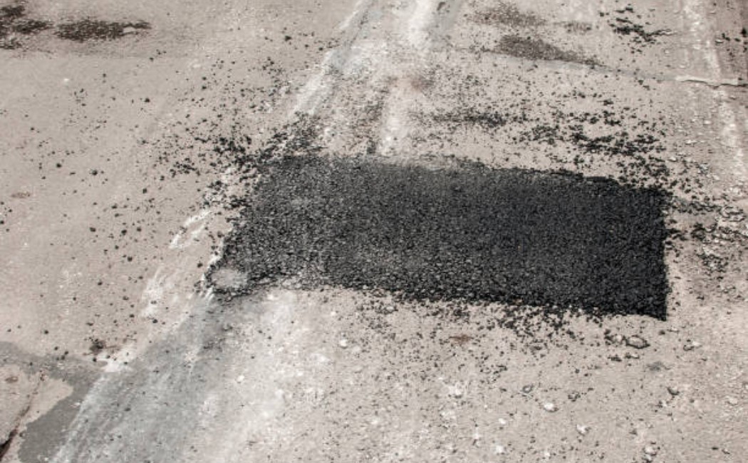 Asphalt road patch repair with fresh tar and tools