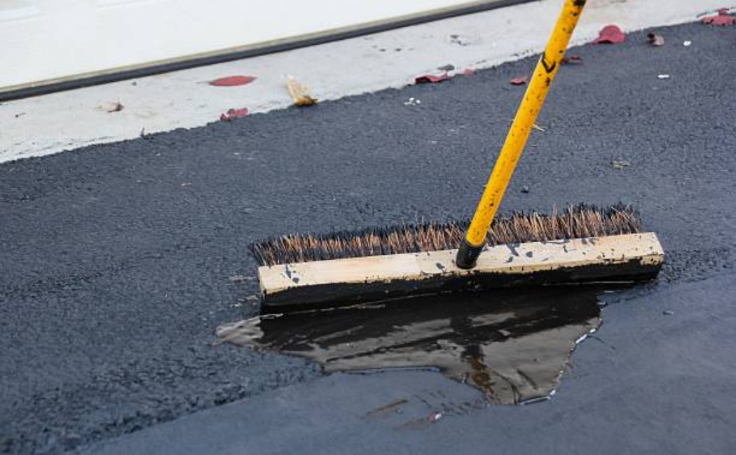 Close-up of brush spreading black driveway seal coating