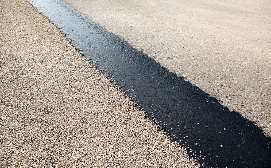 Asphalt street being seal-coated with gravel chips