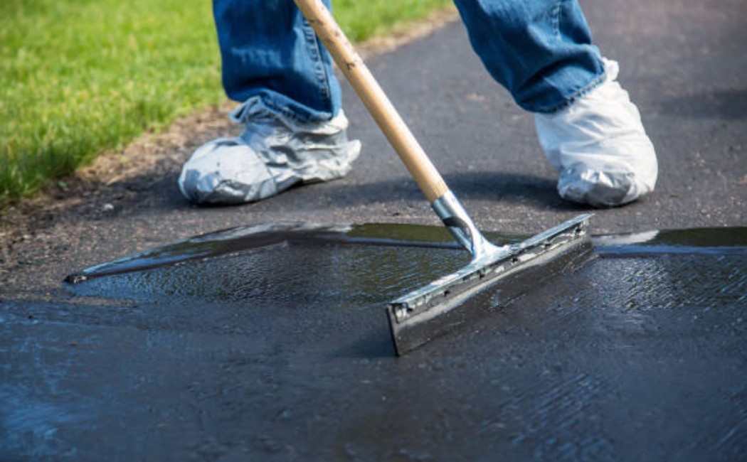 Asphalt driveway receiving a fresh coat of seal coating.