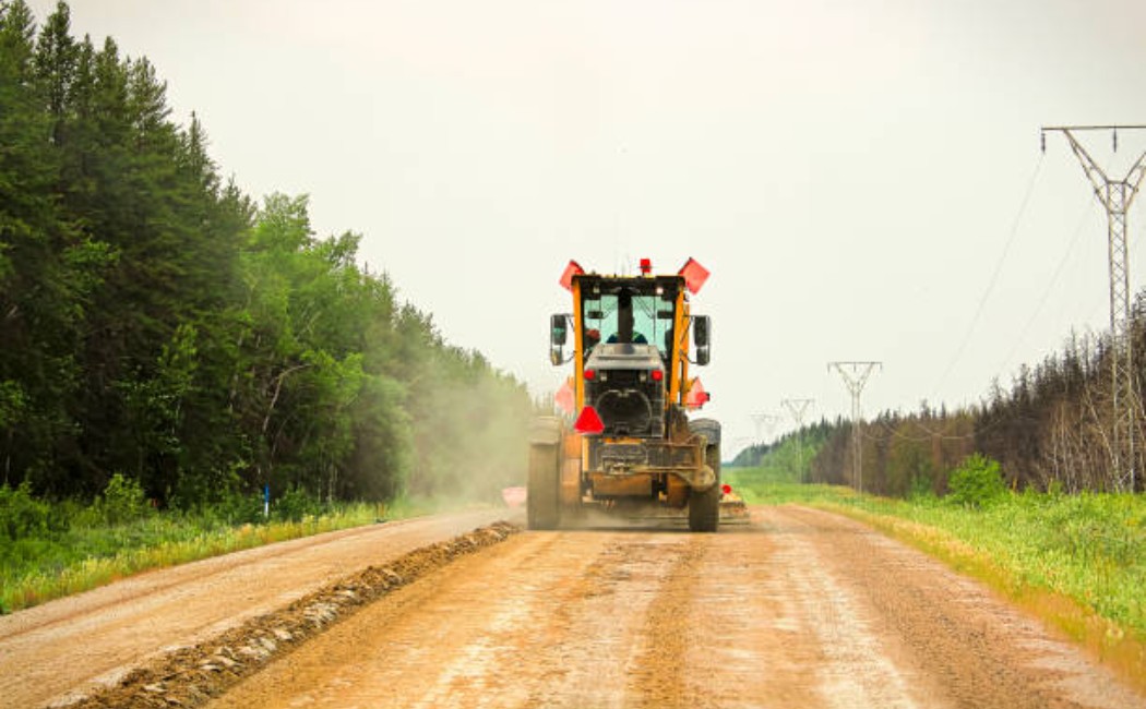Road construction grader shaping gravel surface