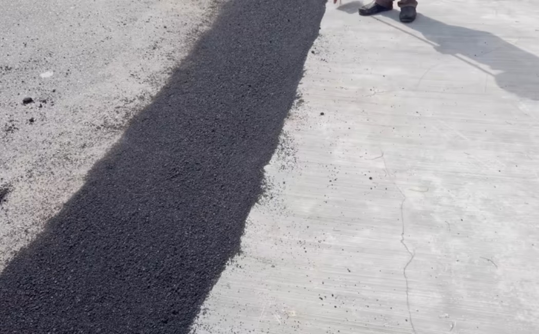 Team constructing smooth black asphalt road with paving machine