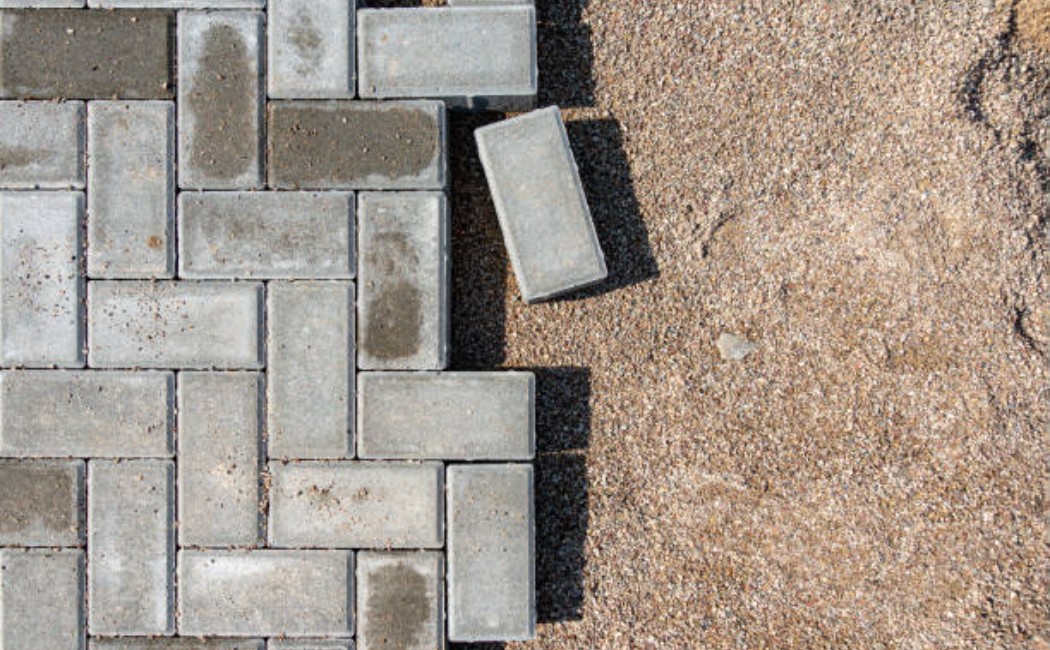 Gray concrete paving slabs are being laid on a garden walkway