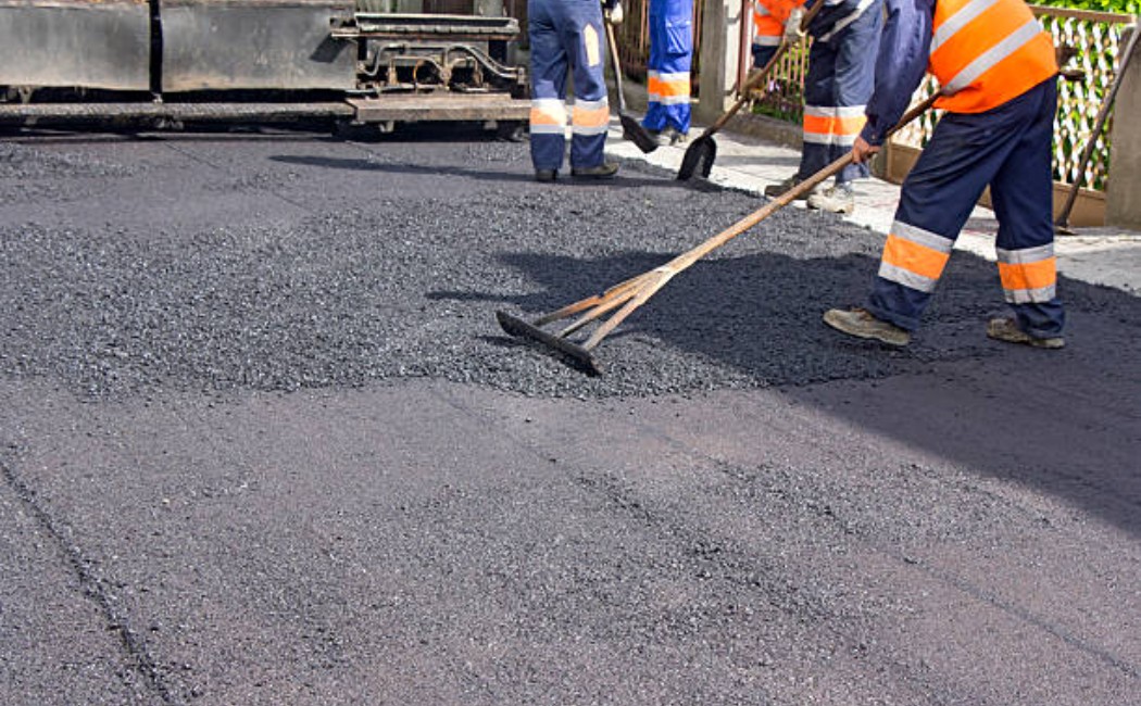 Asphalt paver and workers maintaining a road surface