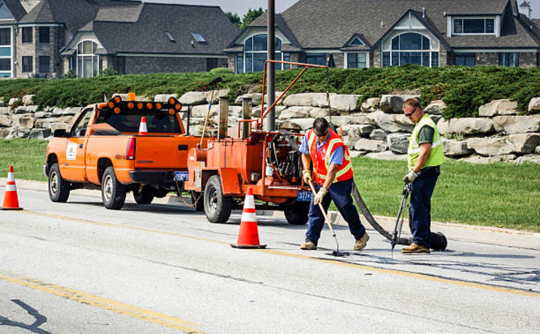 Asphalt road patch repair by construction workers