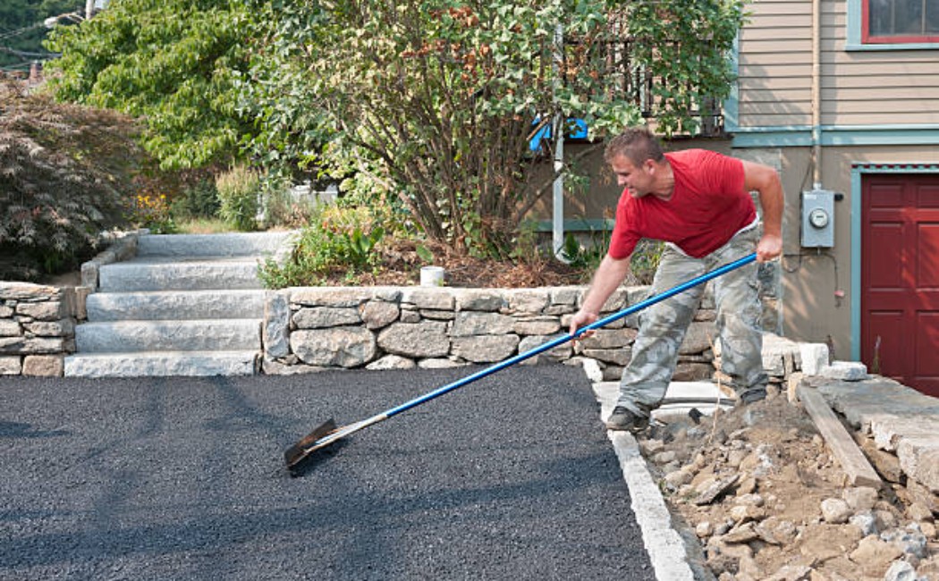 Road paving worker finishing driveway concrete.