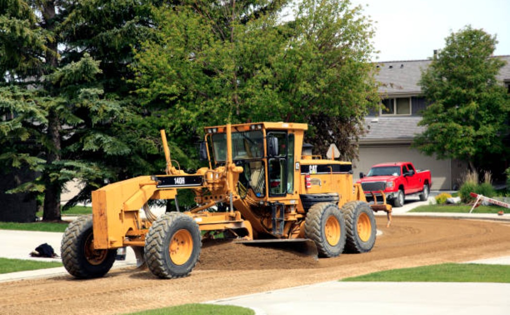 Heavy equipment grading a new residential roadway under construction.