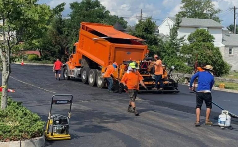 Asphalt Paving Maintenance crew resurfacing a residential street with a paving machine and workers spreading fresh asphalt.