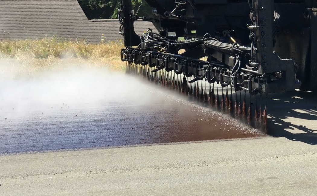 Heavy equipment applying asphalt during professional Chip Sealing Services for durable and smooth road surface protection.