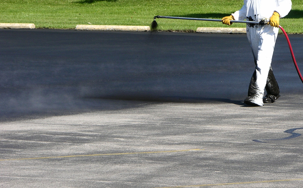 Seal Coating for Durable Asphalt Surface. Seal Coating expert applying a protective asphalt seal coat to a paved surface, enhancing durability, appearance, and resistance to weather damage.