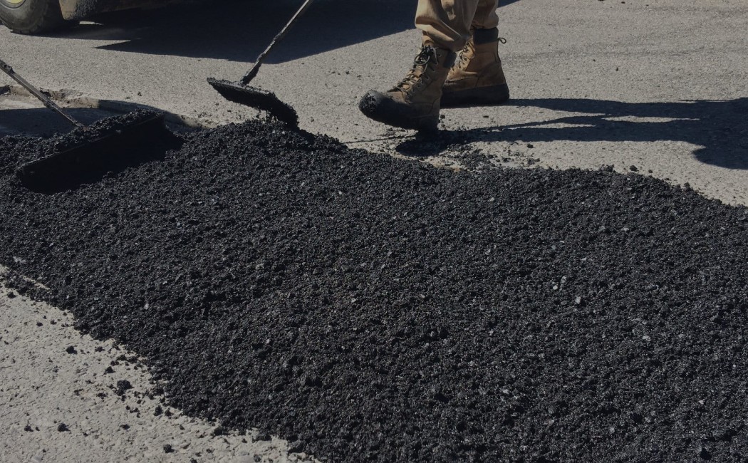 Asphalt resurfacing professionals repairing and renewing a roadway surface with freshly laid asphalt.