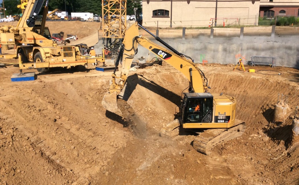 Grading work underway with a large excavator performing excavation and site preparation to create a stable foundation for construction.