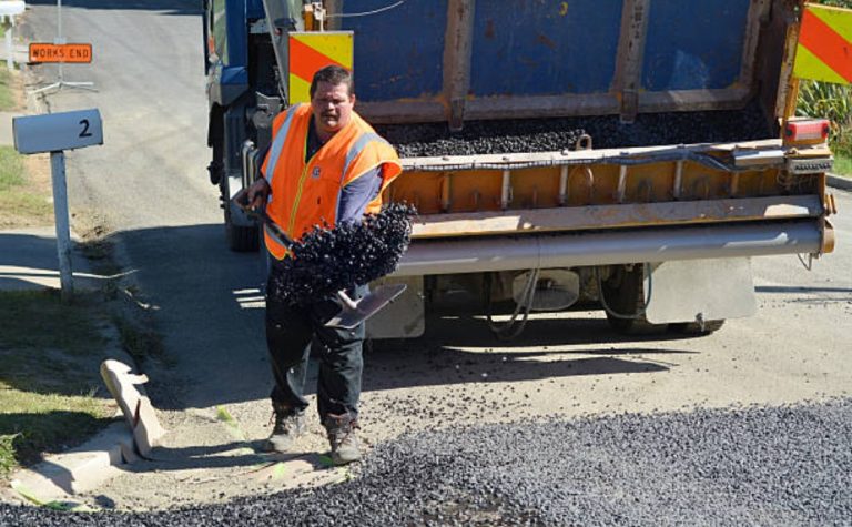 Road construction crew performing professional chip sealing services