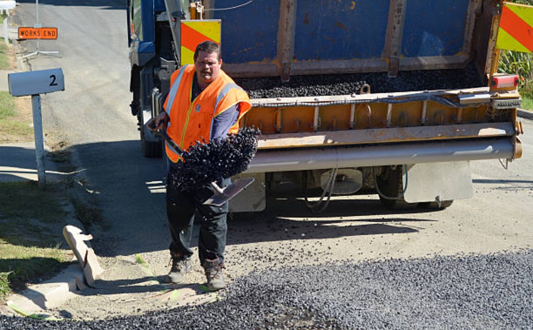 Road construction crew performing professional chip sealing services