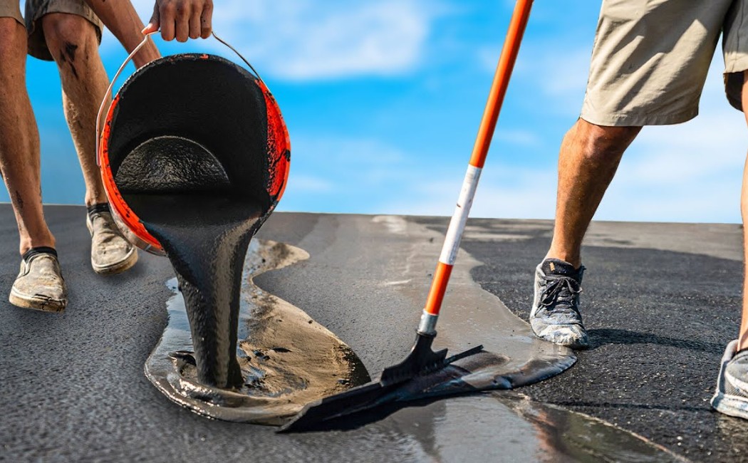 Asphalt repair experts applying and spreading liquid asphalt to restore a damaged pavement surface and improve roadway durability.