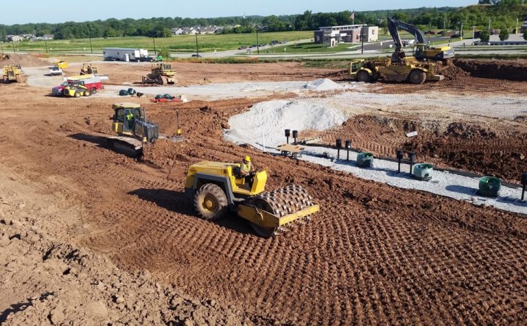 Grading Services crew performing large-scale site grading, soil compaction, and excavation with heavy equipment to prepare land for commercial construction.