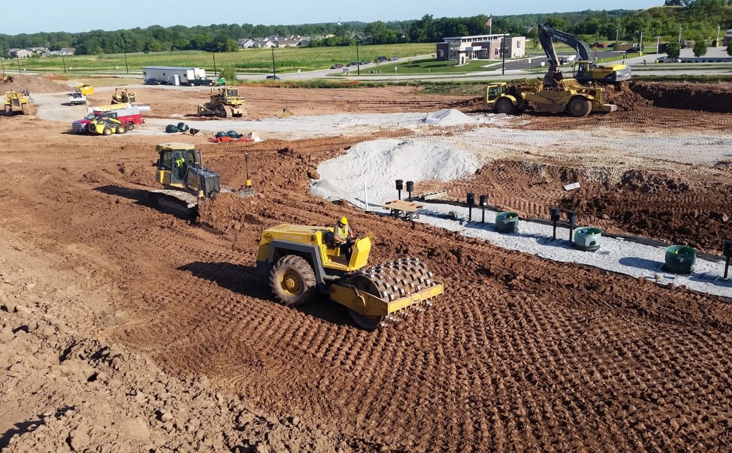 Grading Services crew performing large-scale site grading, soil compaction, and excavation with heavy equipment to prepare land for commercial construction.