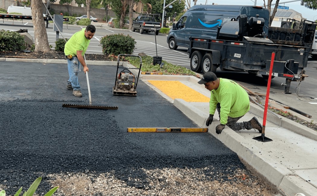 Asphalt Paving for Smooth Parking Lot Surface. Workers performing asphalt paving by leveling and compacting fresh asphalt for a smooth parking lot surface near a sidewalk curb.