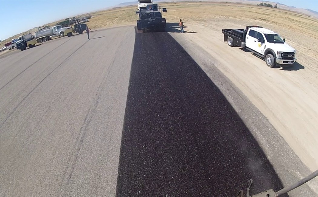 Chip Sealing Crew Protecting Rural Roadway Surface. Construction crew applying chip sealing on a rural roadway for enhanced road protection and a smooth driving surface.