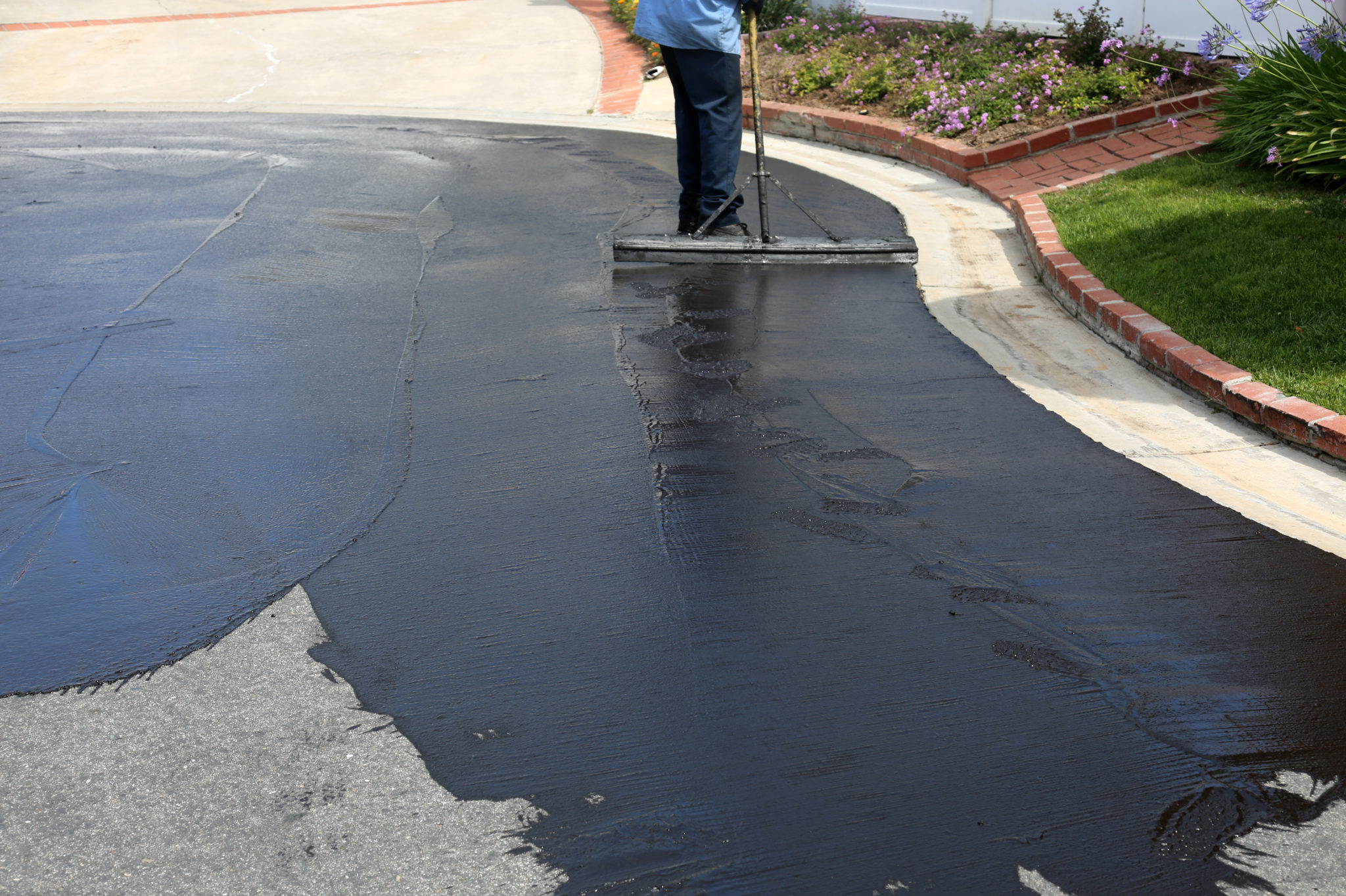 Seal Coating Services applying a fresh protective layer to restore and protect an asphalt driveway.
